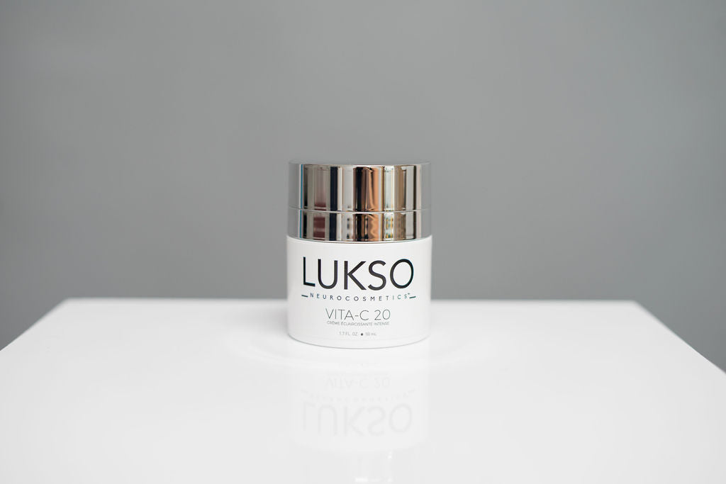 Crème éclaircissante dans un bocal blanc avec le logo de LUKSO NeuroCosmetics en avant et un couvercle métallique 